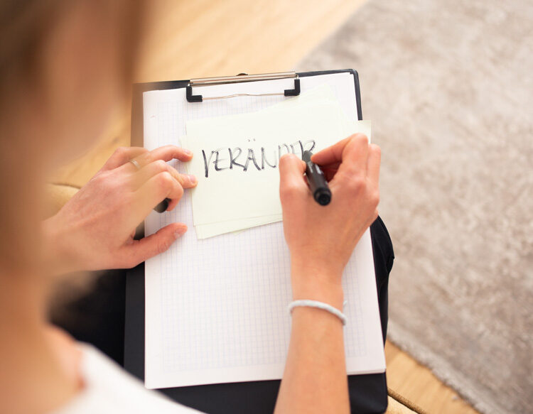 Julia Heinrich über die Schulter fotografiert, wie sie sich eine Notiz macht.